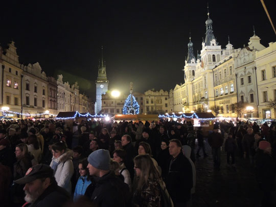 Posluchači harmonie na osvětleném Pernštýnském náměstí s vánočním stromem